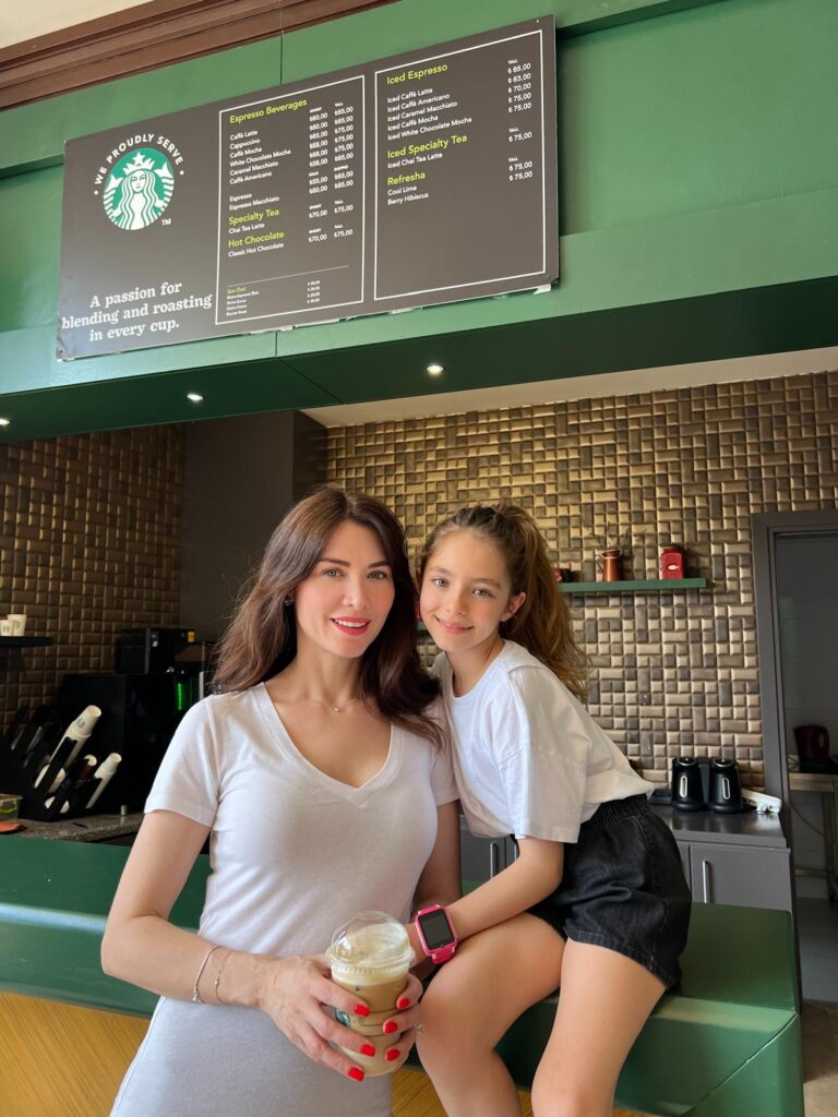 Starbucks menüsü önünde kahveli anne ve kızı gülümsüyor
