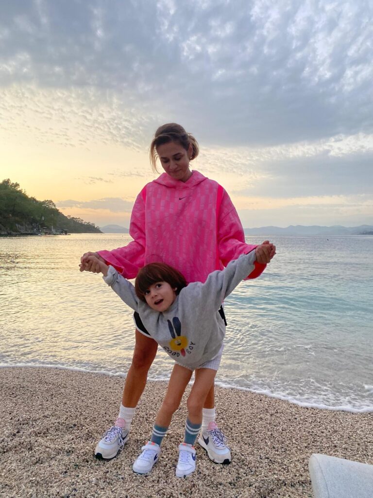 Gün batımında sahilde el ele oynayan mutlu anne ve çocuğu