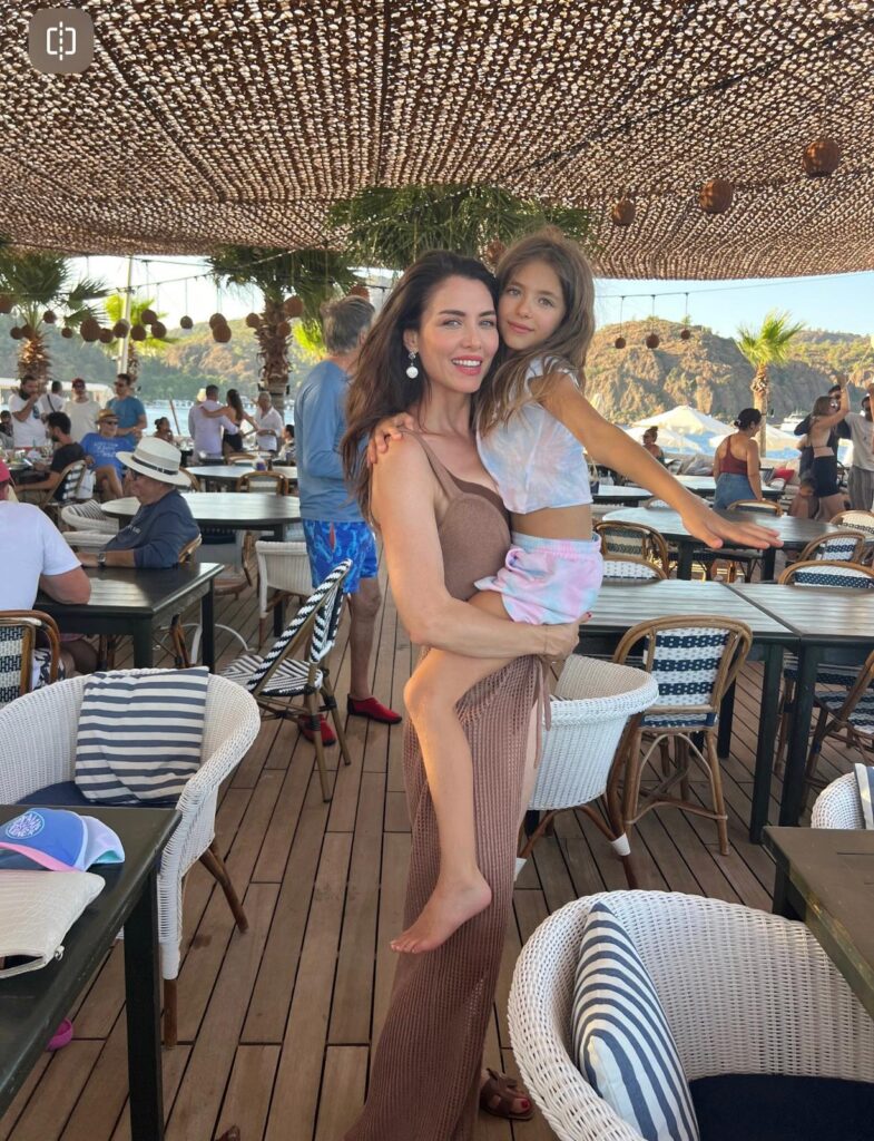Anne ve kızı açık hava kafede dokuma tente altında gülümsüyorlar