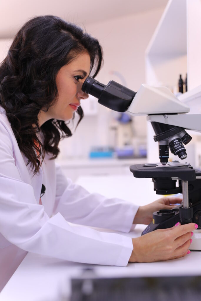 Bir kadın laboratuvarda mikroskopla dikkatlice örnek inceliyor