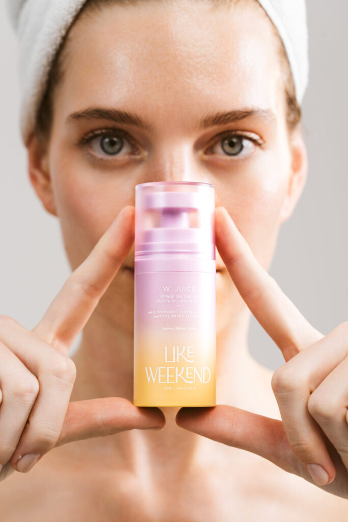 Bir kadın W. JUICE LIKE WEEKEND cilt bakım ürününü tutuyor