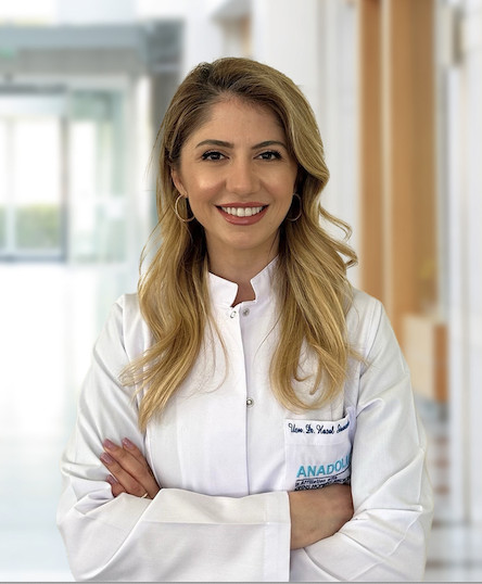 Beyaz önlüklü gülümseyen kadın doktor hastane ortamında poz veriyor