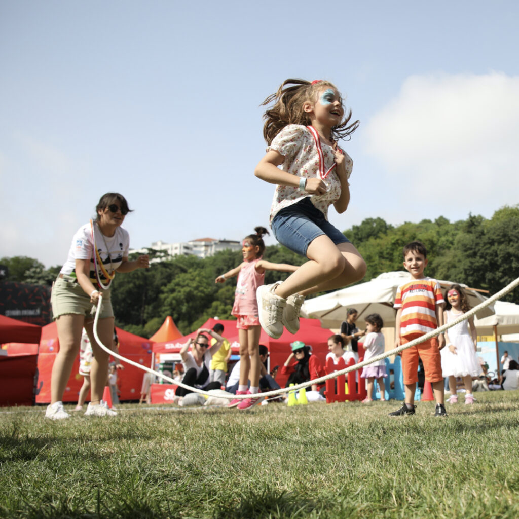 Güneşli bir günde ip atlayan neşeli çocuk festivalde eğleniyor