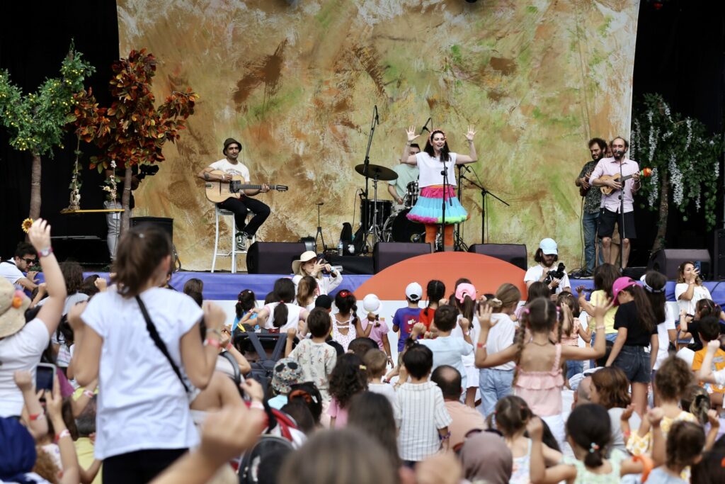 Çocuklar sahnede canlı müzik performansı izlerken coşkuyla eğleniyorlar