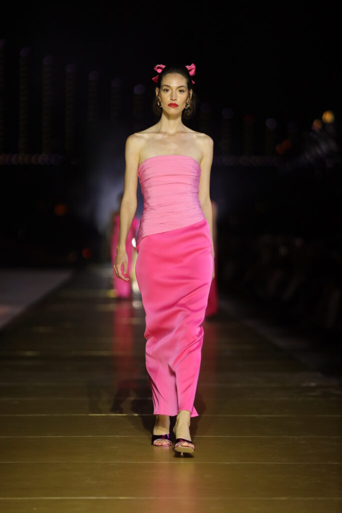 Podyumda pembe straplez elbise ve fiyonklarla yürüyen model
