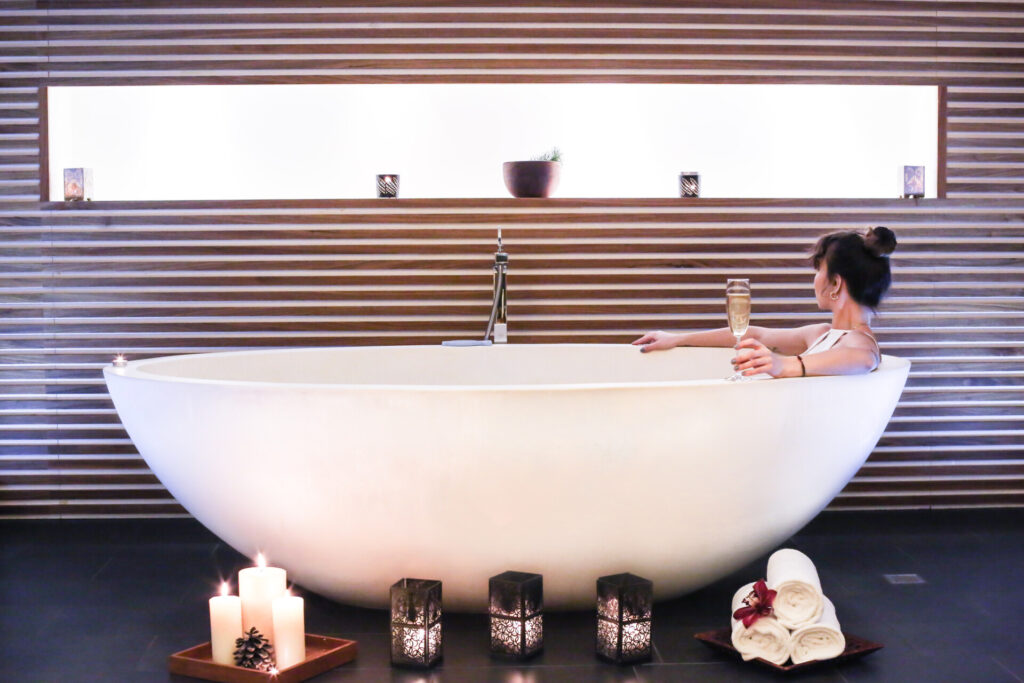 Lüks spa küvetinde mumlar ve şampanya ile rahatlayan kadın