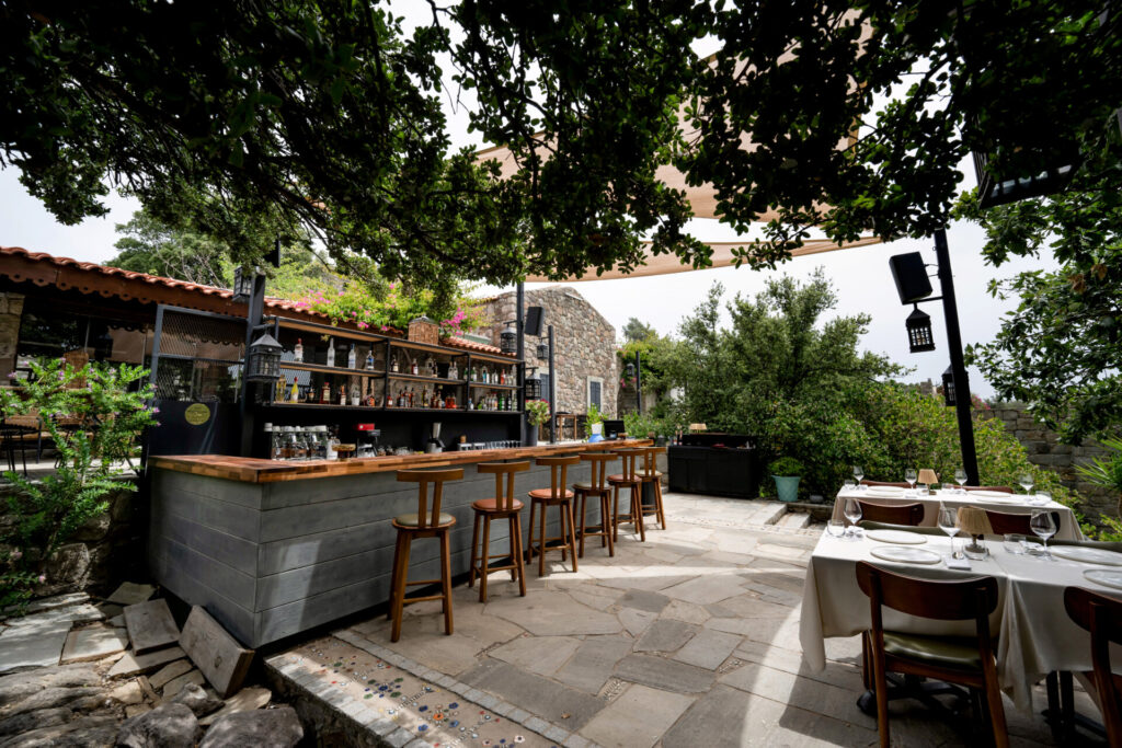 Gölgede taş döşeli bir avluda bar ve masa düzeni
