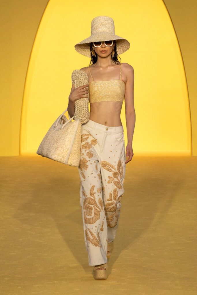 Sarı podyumda hasır şapka crop top ve işlemeli pantolonlu yazlık kombin