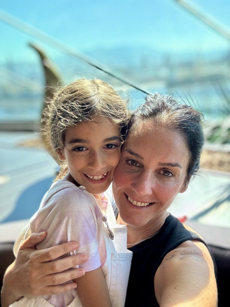 Mutlu anne ve kızı güneşli havada sarılarak kameraya gülümsüyorlar
