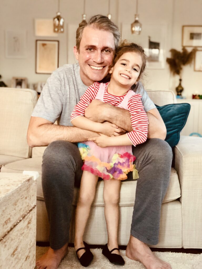 Baba ve kızı kanepede oturmuş sarılarak kameraya gülümsüyorlar