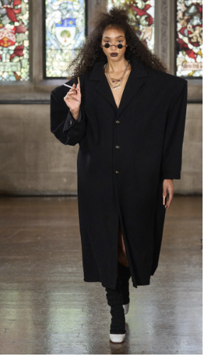 Siyah oversize palto yuvarlak gözlük ve kıvırcık saçlı model elinde sigara