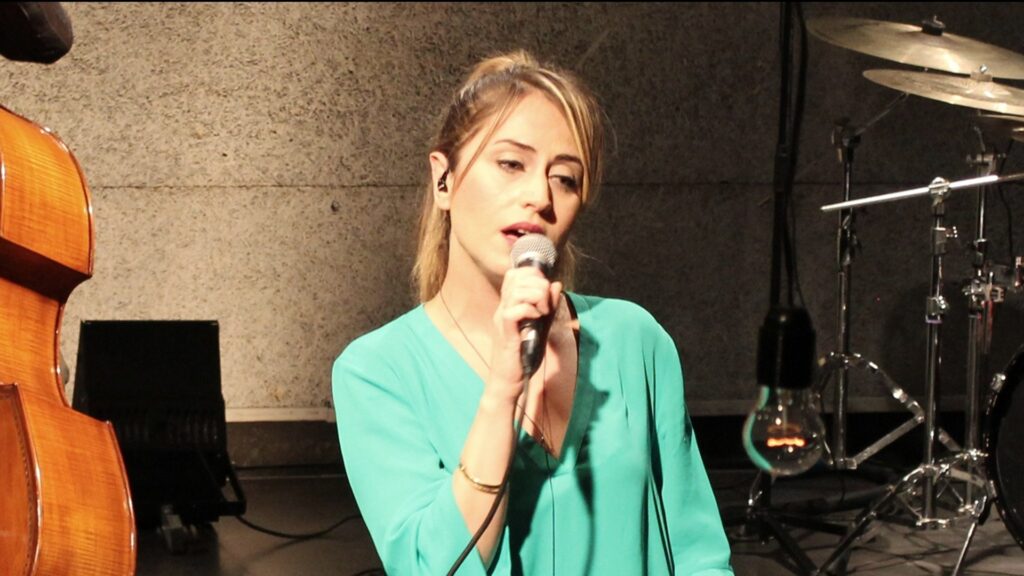 Canlı müzik ortamında şarkı söyleyen kadın, mikrofon, bas ve davullar