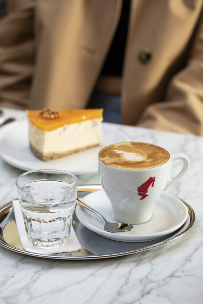 Mermer masada latte artlı kahve portakallı cheesecake ve su bardağı
