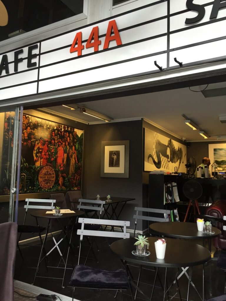 Cafe 44A dışarıdan girişi, masalar, sandalyeler ve iç mekan sanatı