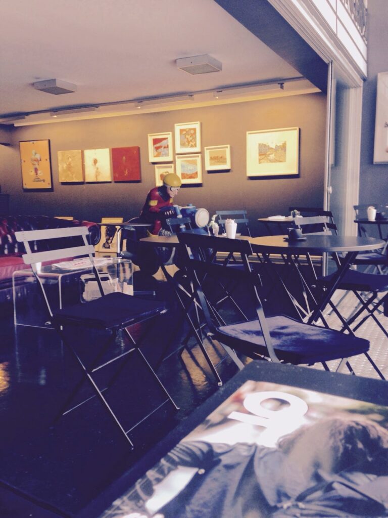 Sanat eserleri ve masada kasklı manken figürü olan kafe iç mekanı