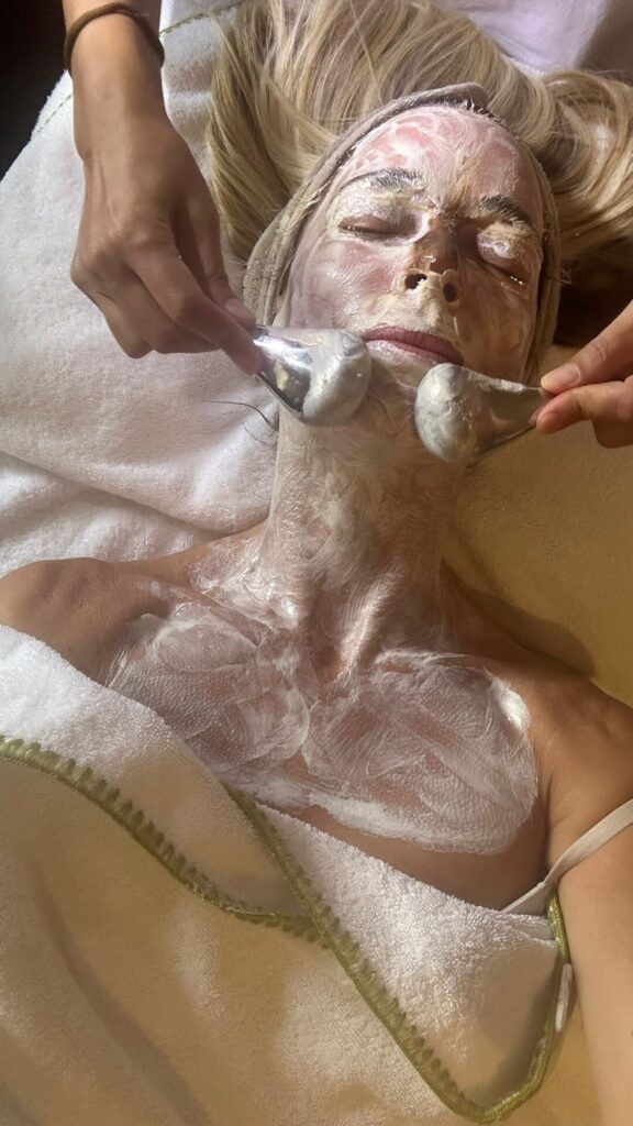 Yüz ve boyun maskesi uygulanan bir kişi masaj aletleriyle cilt bakımı alıyor