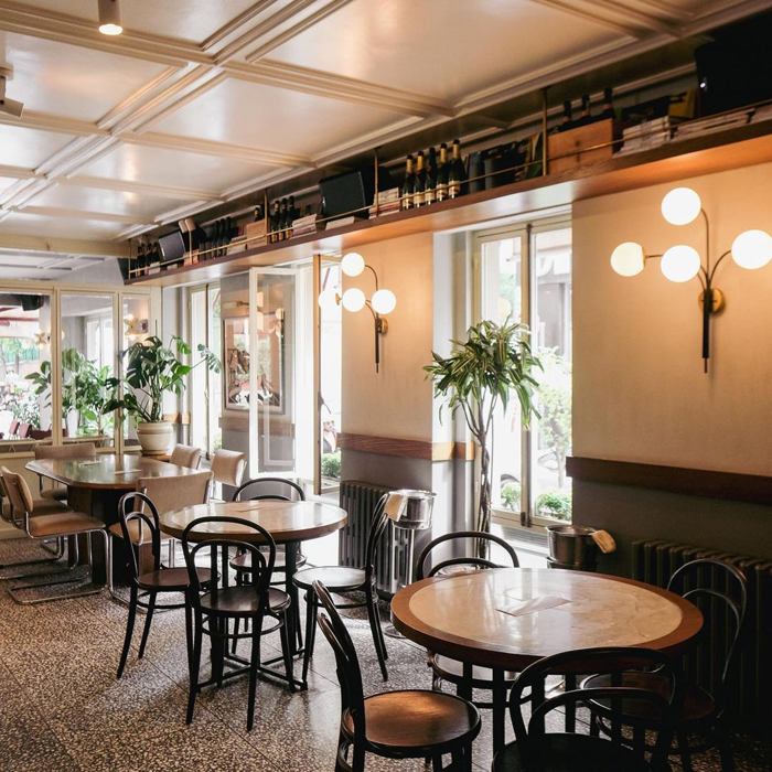 Şık bir kafe veya restoranın içi masalar, sandalyeler ve bitkilerle dolu