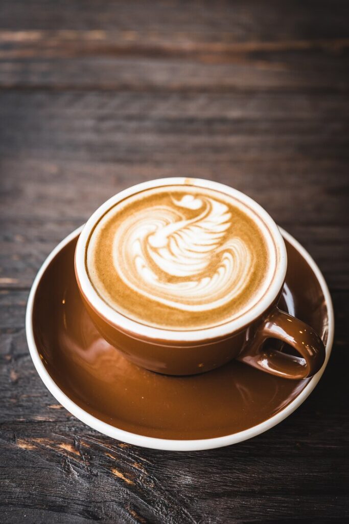 Kuğu desenli latte sanatı kahve kahverengi fincanda ahşap zeminde