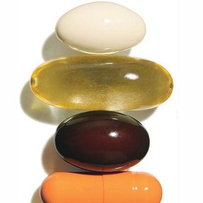 Dikey olarak dizilmiş dört farklı renkli vitamin ve takviye kapsülü
