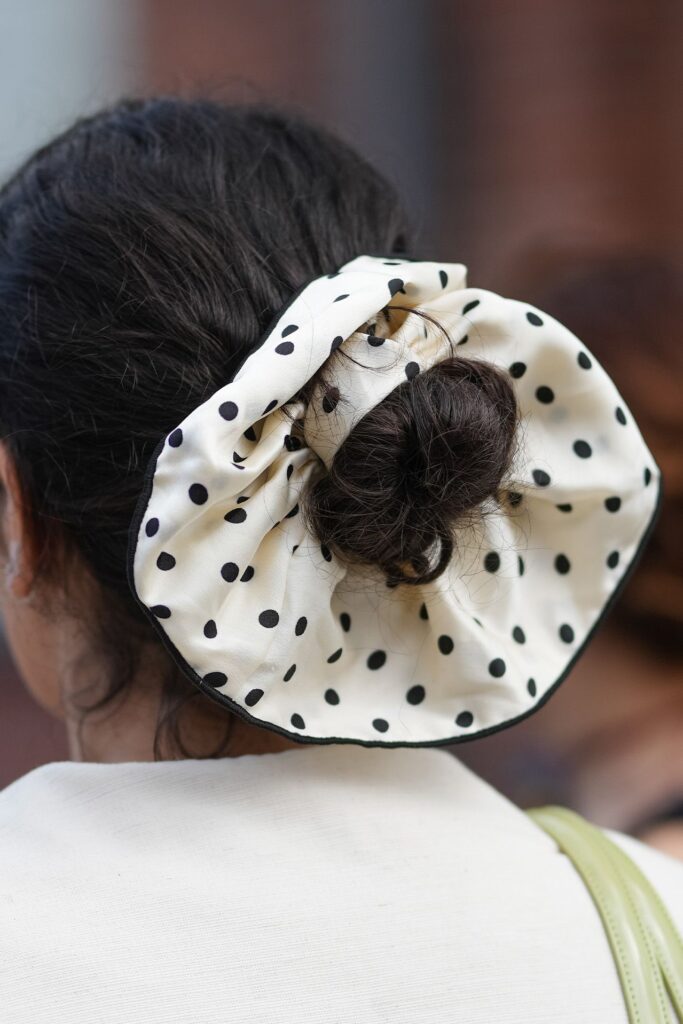Arkadan görünen puantiyeli beyaz scrunchie ile toplanmış koyu saç topuzu