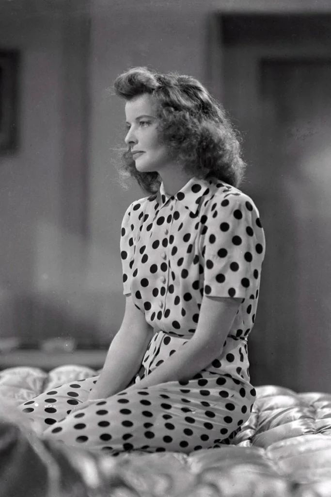 Genç Katharine Hepburn puantiyeli elbise içinde oturmuş dalgın bakıyor
