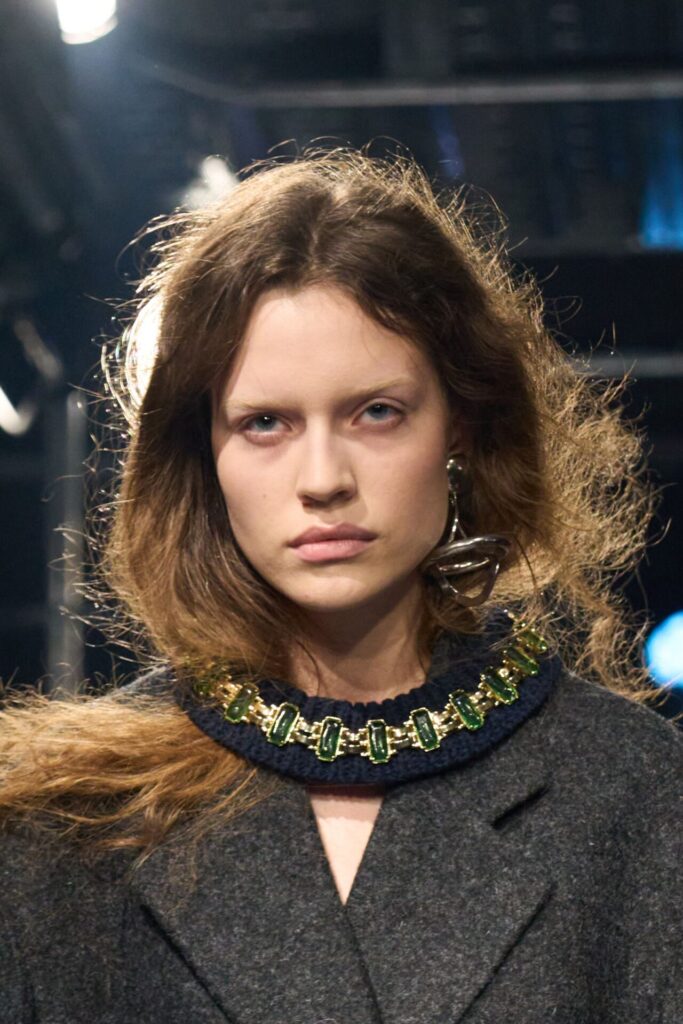 Uzun saçlı model gri kaban ve yeşil taşlı choker kolye takıyor