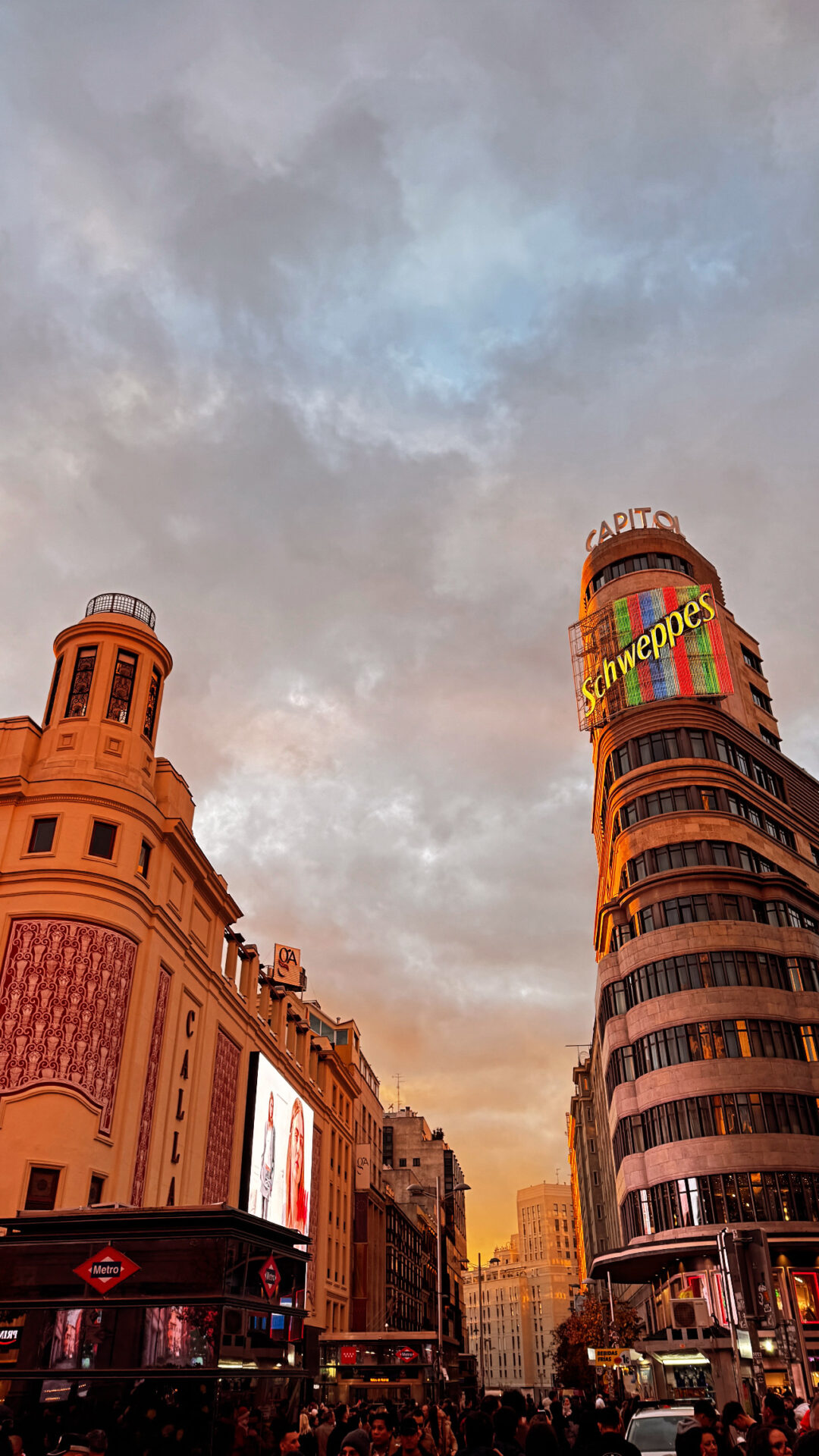 Madrid'de akşamüstü Schweppes tabelalı tarihi bina ve hareketli cadde