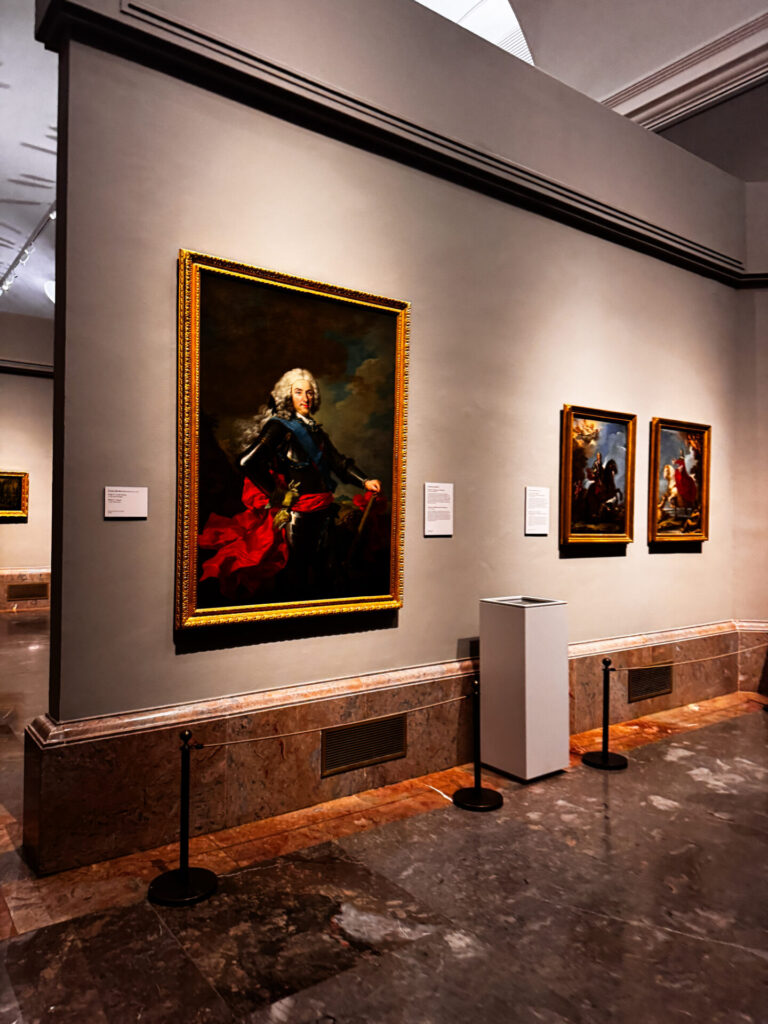 Müze galerisinde beyaz peruklu bir adamın portresi ve sanat eserleri