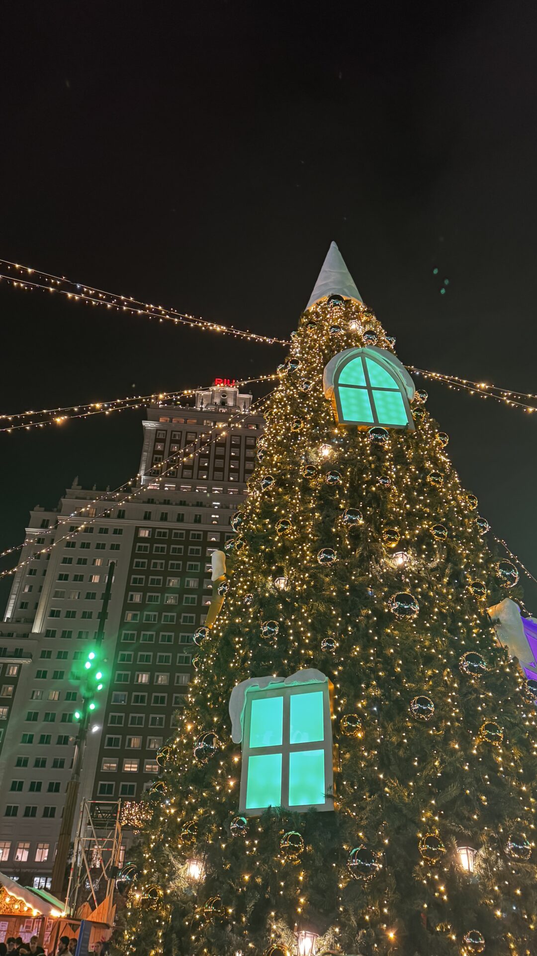 Gece süslü Noel ağacı, arkada bina ve asılı ışıklar