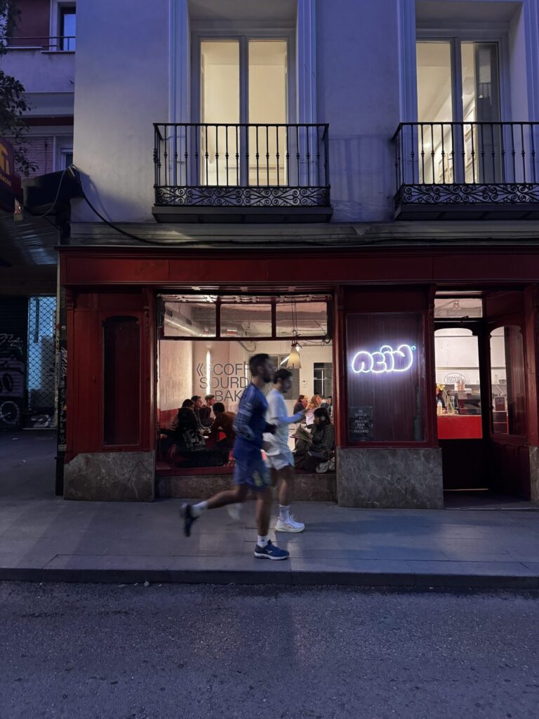 Akşam karanlığında kırmızı kafe önünden geçen bulanık iki insan