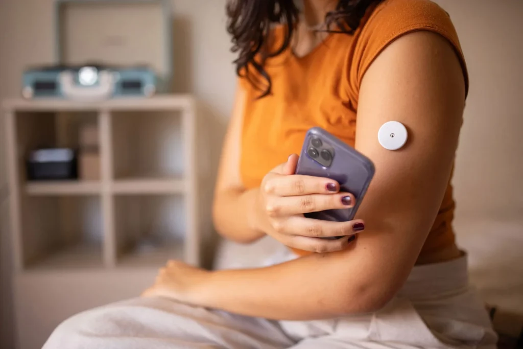 Kolunda şeker monitörü olan telefon kullanan genç bir kadın
