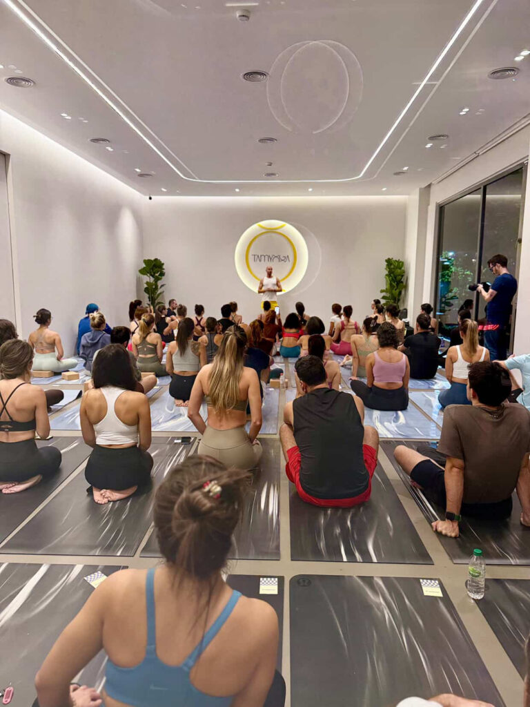 Yoga stüdyosunda eğitmen önünde oturan kalabalık grup dersi