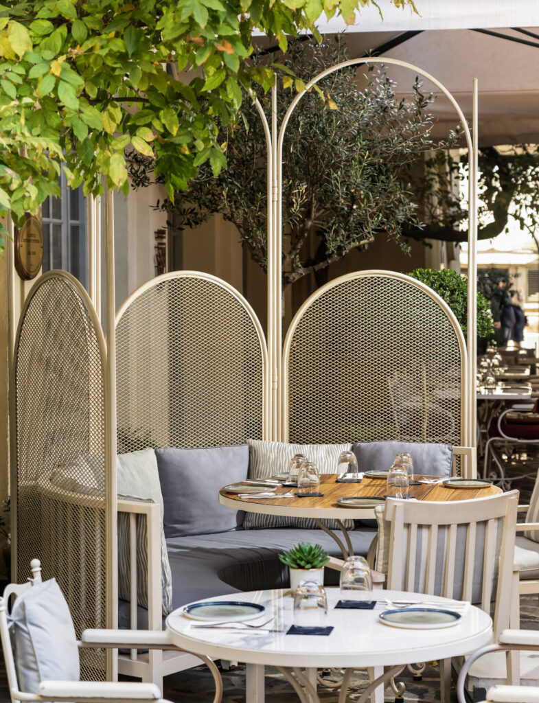 Yeşillikler içinde modern bir dış mekan restoranında şık masalar ve oturma düzeni