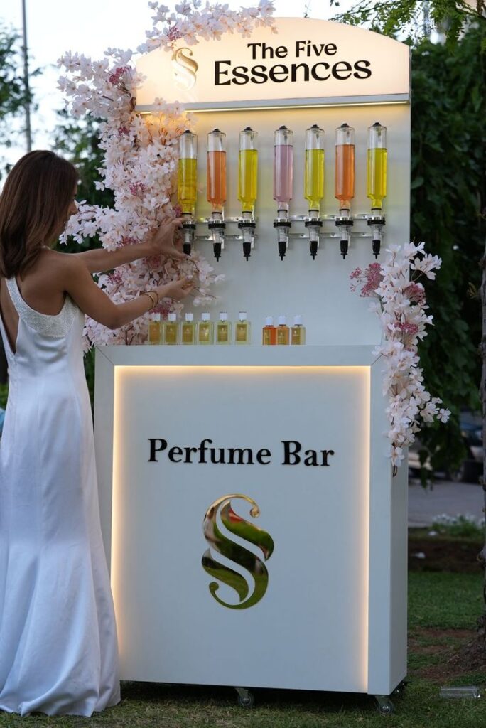 Zarif beyaz elbiseli kadın çiçekli The Five Essences parfüm barı