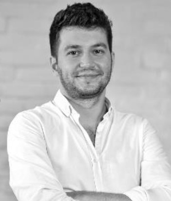 Yakışıklı sakallı adam beyaz gömlekli gülümseyerek kameraya bakıyor
