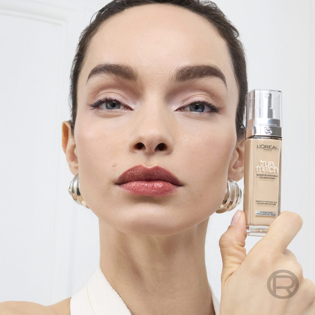 L'Oréal True Match fondötenini tutan makyajlı genç kadın yakın çekim