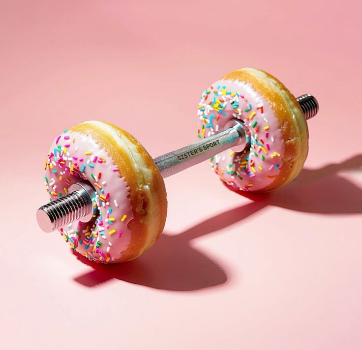 Pembe sırlı ve şekerlemeli donutlardan yapılmış dambıl, pembe arka plan